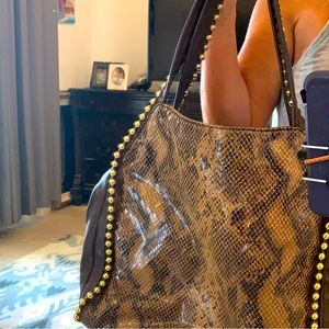 Faux snakeskin brown with nail heads in gold trim. Hobo bag style